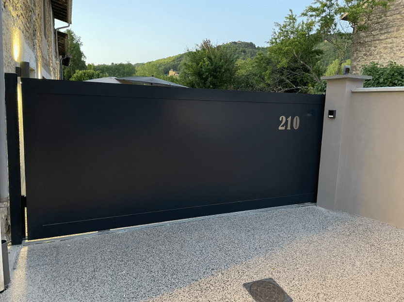 Portail coulissant motorisé en aluminium gris foncé numéroté 210, installé à l'entrée d'une propriété résidentielle